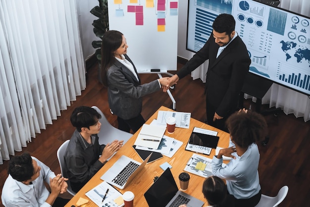 Diverse coworker celebrate with handshake and teamwork in corporate workplace Happy business people united by handshaking after successful meeting or business presentation on data analysis Concord