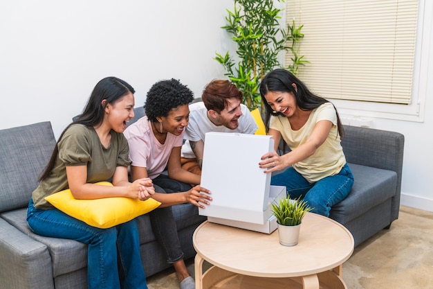 Diverse friends sharing the joy of opening a pizza box together in a comfortable living room smiling