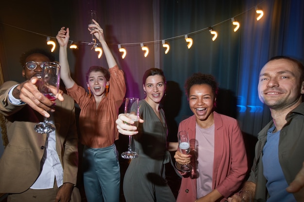 Diverse group of carefree people dancing while enjoying party indoors, shot with flash