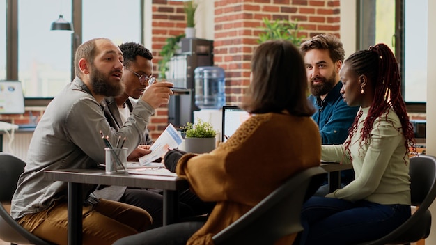 Diverse group of coworkers planning startup project in boardroom, meeting to work on business collaboration. People brainstorming ideas to create research analysis and files report. Tripod shot.