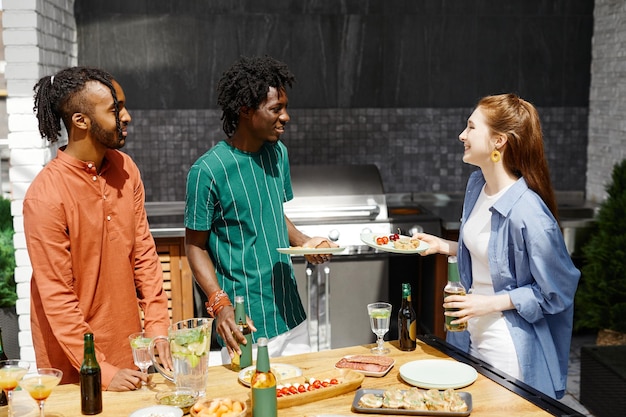 Diverse group of friends enjoying dinner party at outdoor terrace in sunlight