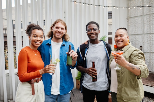 Diverse group of modern young people looking at camera while having fun at outdoor rooftop party