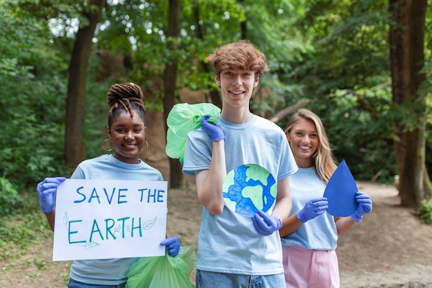 Diverse Group of People Picking Up Trash in The Park Volunteer Community Service Happy international volunteers holding placard with 'Save the Earth' message