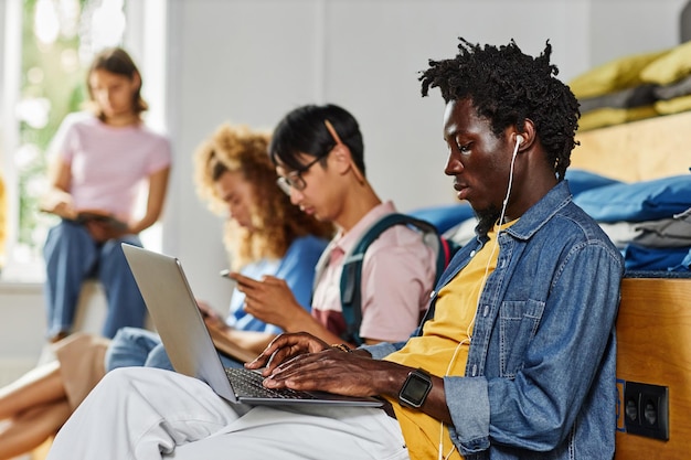 Diverse group of students in row studying focus on african american young using laptop in foreground