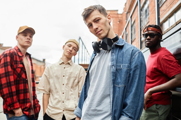 Diverse group of young men wearing streetstyle and looking at camera outdoors all male team