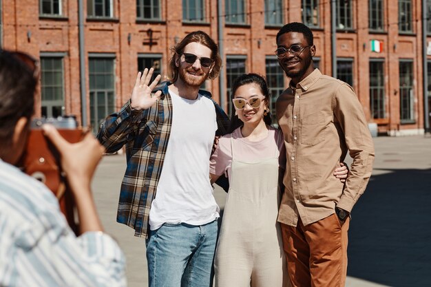 Diverse group of young people taking photo outdoors in city street lit by sunlight