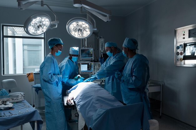 Diverse male and female doctors wearing face masks and surgical overalls in operating theatre