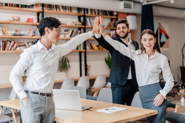 Diverse team of business people giving high five to each other 