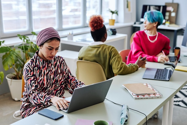 Diverse team of software developers with Muslim young woman using computer