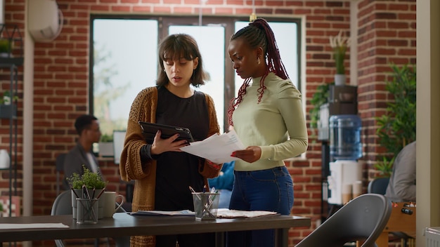 Diverse team of women planning online business project with research data and charts information in office. Brainstorming ideas to create startup presentation and report, collaboration work.