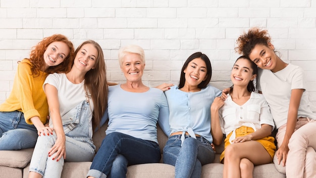 Photo diverse women of different age sitting on sofa smiling to camera indoor support group concept