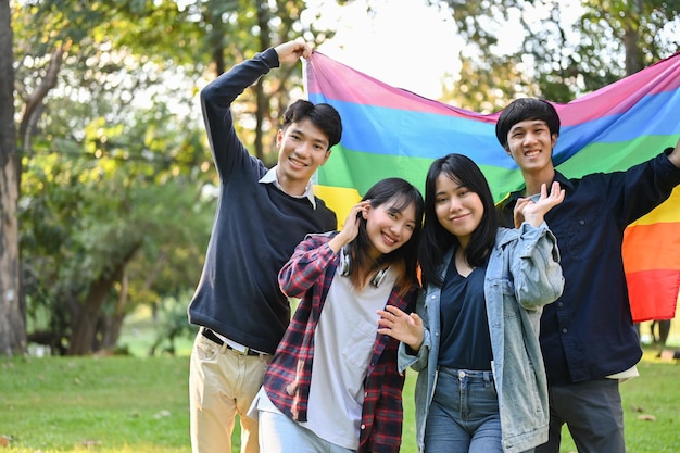 Diverse young college students holding LGBT rainbow flag together in the park LGBTQ pride