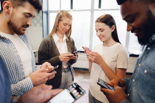 Diverse young people colleagues working on mobile phones together in office