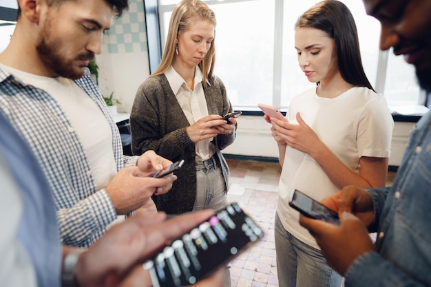 Diverse young people colleagues working on mobile phones together in office