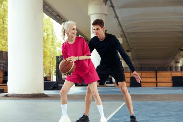 Diversity guy and girl playing basketball on the city playground