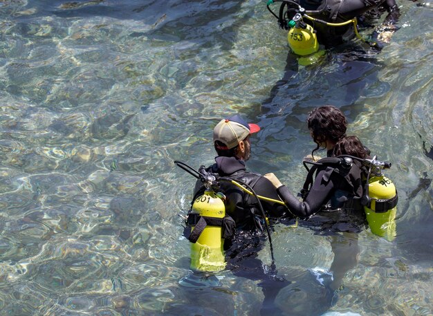 Diving with aqualung lesson in open water Scuba diver instructor before diving into deep sea Waiting on the surface before free diving Male and women in scuba diving suit is preparing to dive