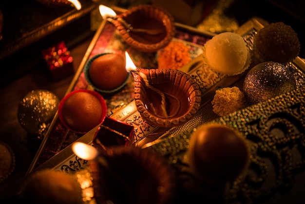 Diwali diya or lighting in the night with gifts, flowers over moody scene