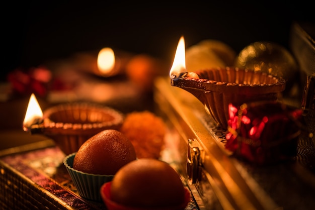 Diwali diya or lighting in the night with gifts, flowers over moody scene