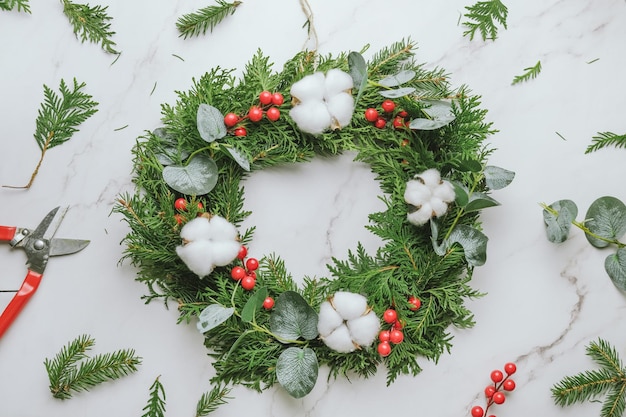 DIY Christmas wreath with evergreen twigs cotton balls and holly berries