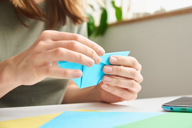 DIY concept. Woman make origami easter rabbit from color paper. Origami lessons