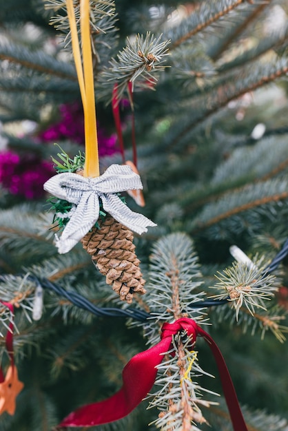 DIY handmade pine cone and ribbon bow decoration on Christmas tree