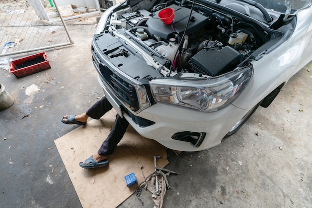 DIY Mechanic lying and working under car at home garage 