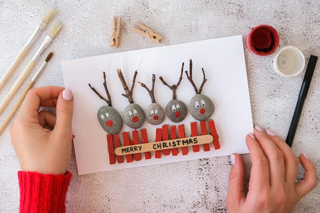 Photo diy merry christmas deer on greeting card postcard made of pebbles sea stones clothespins