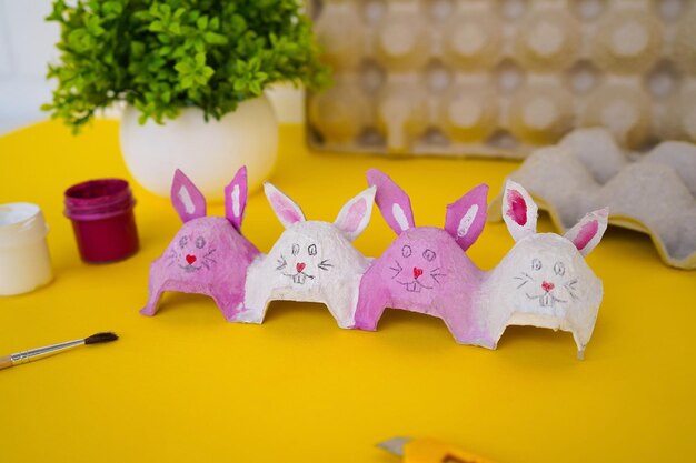 Photo diy pink and white bunnies made of cardboard packaging from eggs zero waste concept easter crafts