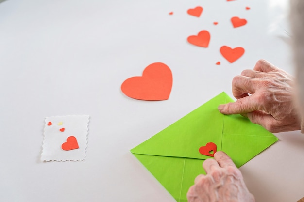 DIY valentines day card Senior woman hands are closing an envelope