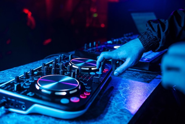 DJ console for mixing music with hands and with blurred people dancing at a night club party