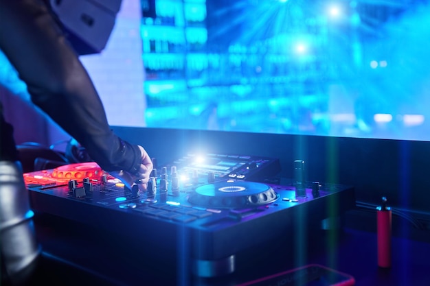 Dj girl playing music with turntables and sound mixer on stage in night club