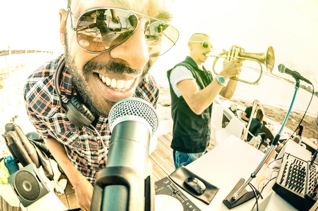 Dj playing summer hits at sunset beach party with trumpet jazz performer