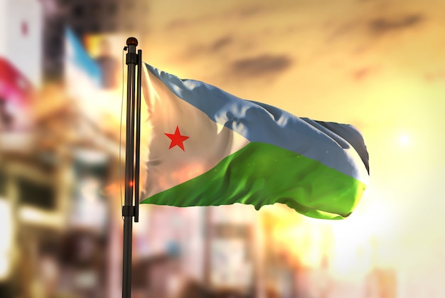 Djibouti Flag Against City Blurred Background At Sunrise Backlight