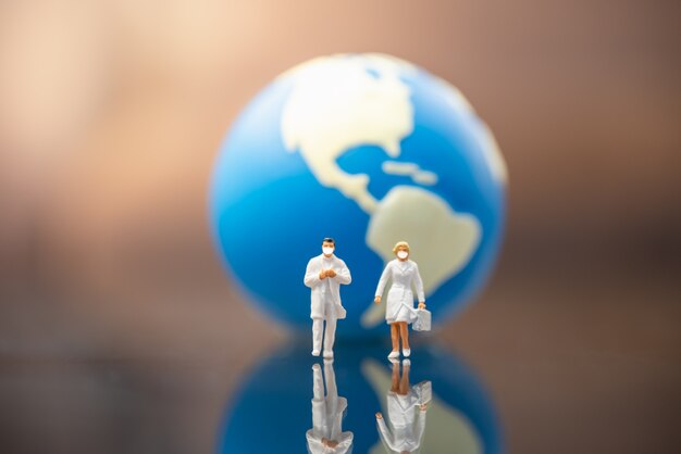 Docter and nurse miniature figure people walking with mini world ball as background.