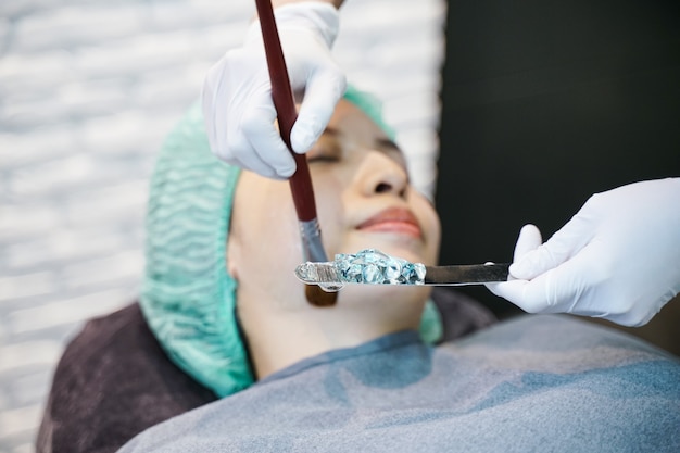 Doctor applies Hydro gel Mask on the woman face. Before young woman receiving laser treatment.