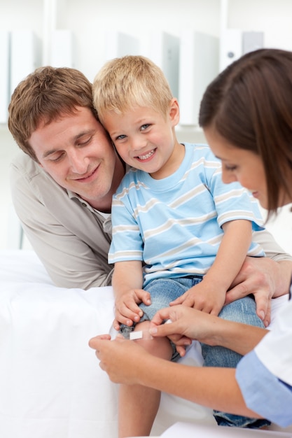 Doctor applying a plaster on a smiling boy's knee