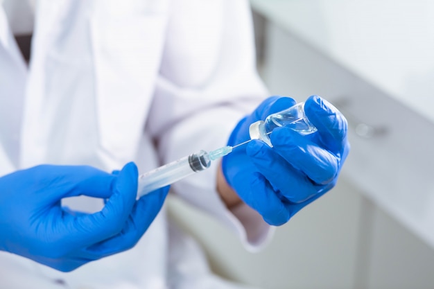 Doctor in blue glove filling syringe with vaccine