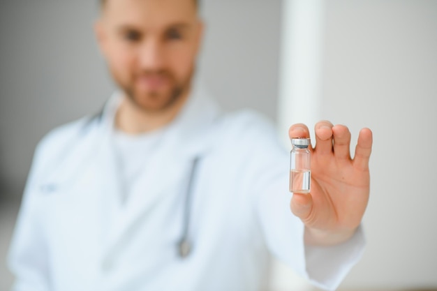 A doctor in blue gloves holding a bottle with vaccine Close up shot Medicine and healthcare concept