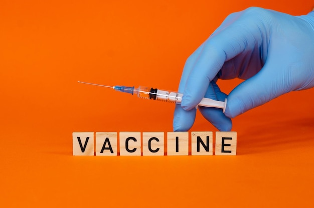 Doctor in blue latex gloves fill in syringe with medicine from glass vial, closeup. Making a vaccine