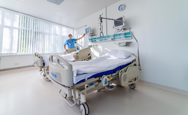 Doctor in blue medical clothes and mask is looking at the screen with health parameters on it Medical chamber First aid Reanimation