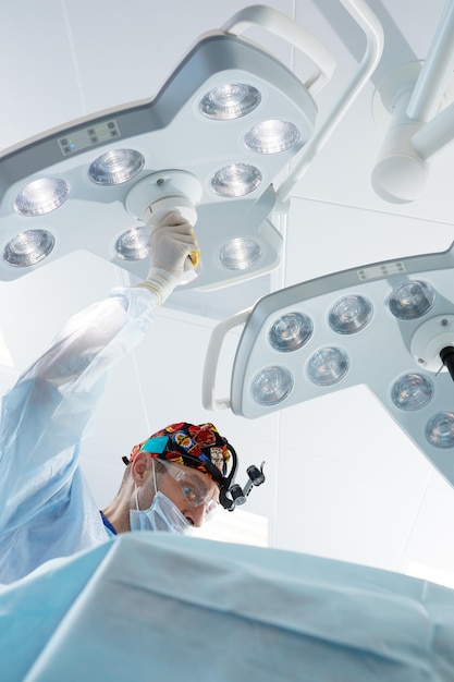 Doctor in blue surgical gown inside operating room before doing surgery The light form lamp on background with copy space Medical concept