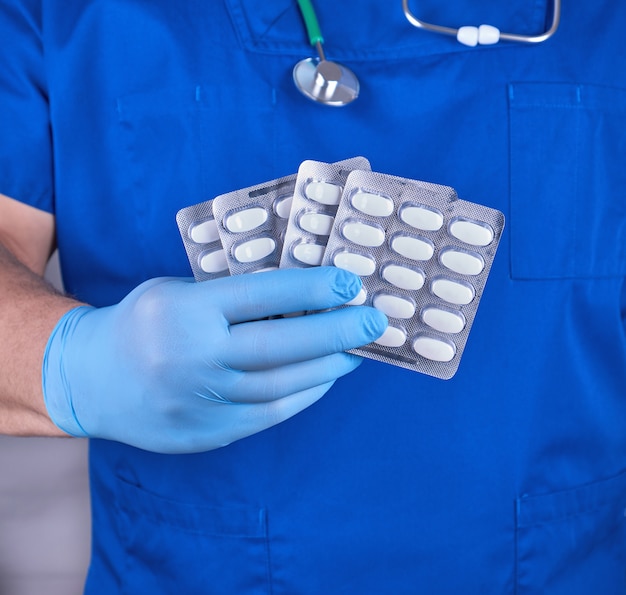 Doctor in blue uniform and sterile gloves holding pills