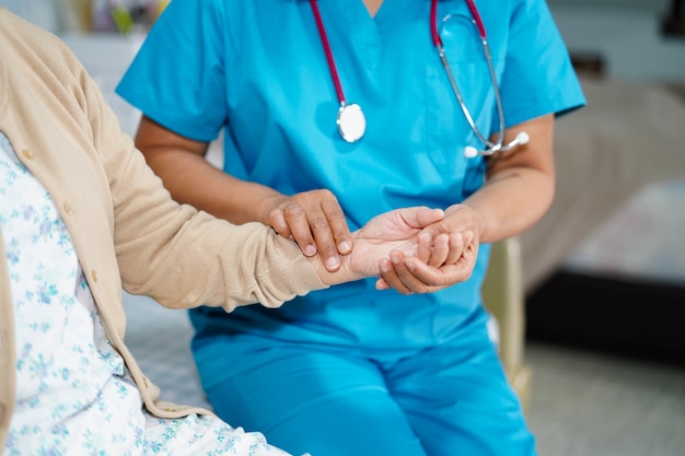 Doctor catching the pulse with patient in nursing hospital