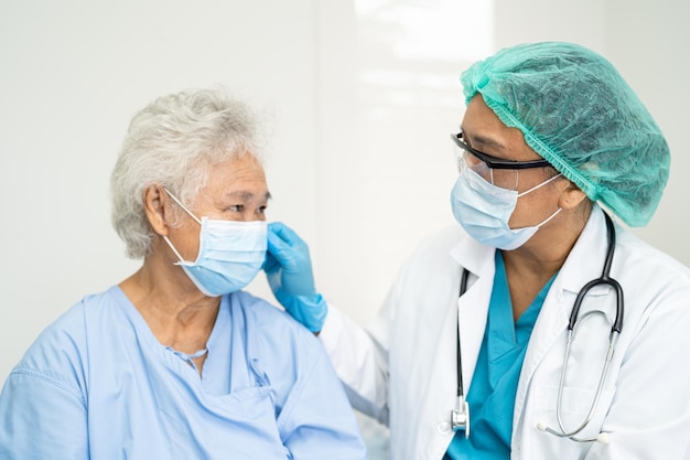 Doctor checking Asian senior woman patient wearing a face mask in hospital for protect Covid19 Coronavirus