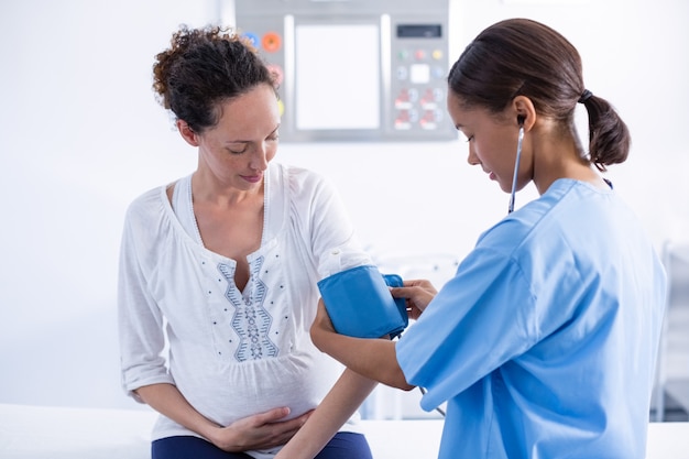 Doctor checking blood pressure of pregnant woman