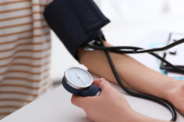 Doctor checking blood pressure of woman in clinic closeup