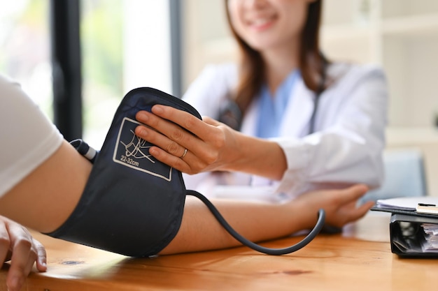 A doctor checking patient's pulse and blood pressure with a monitor in the examination room