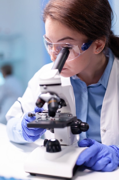 Doctor chemist researcher in white coat working with microscope in clinic discovery