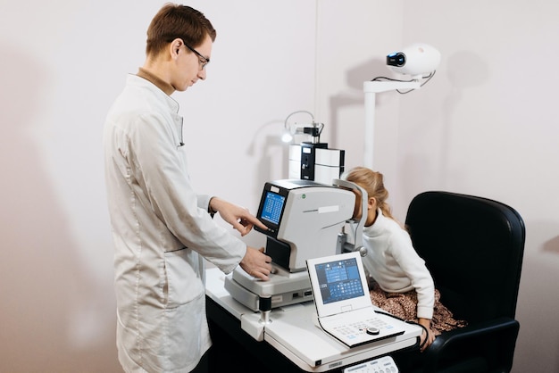 A doctor and a child are working on a microscope look at an eye exam with a doctor