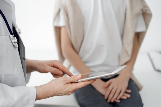 Doctor and child patient. The doctor is using tablet computer and is ready to examine the boy. The concept of ideal health in medicine